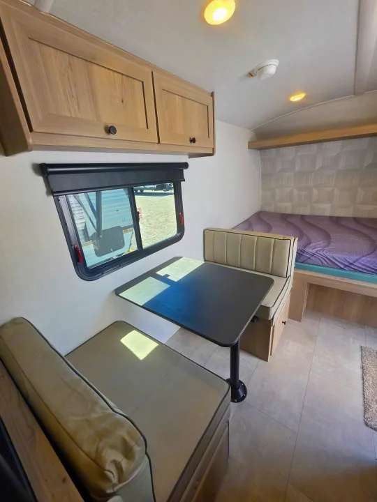 RV rental interior: cozy dinette seating, overhead cabinets, and a comfortable bed for travel adventures.. Forest River Rockwood Geo Pro 2026