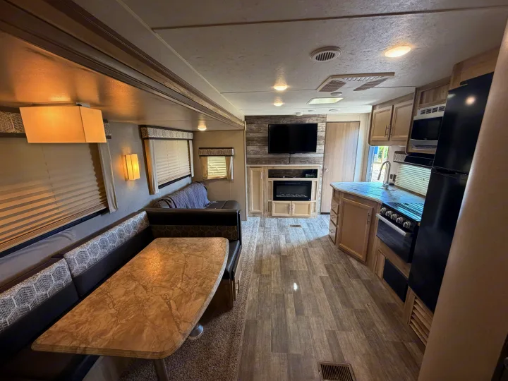 Cozy RV rental interior with a modern kitchen, dining booth, and living area featuring a TV and fireplace.. Coachmen Other 2021