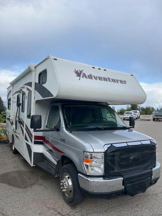 Silver & white Adventurer Class C rv rental with a Ford chassis, parked on asphalt under a cloudy sky.. Adventurer Adventurer Motorhome 2016