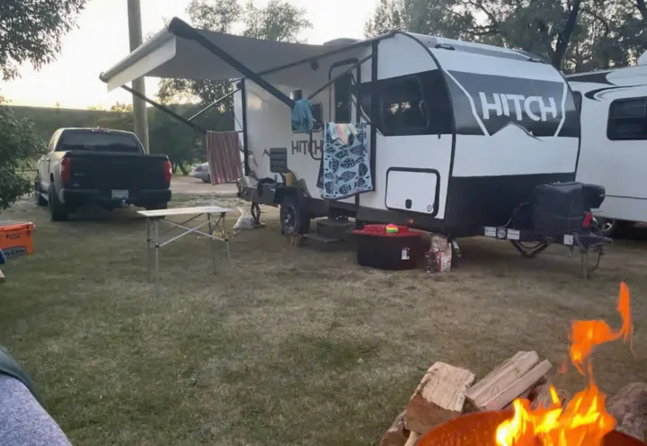HITCH rv rental travel trailer at a grassy campsite with a pickup truck and a warm campfire, perfect for camping.. Cruiser RV Hitch 2022