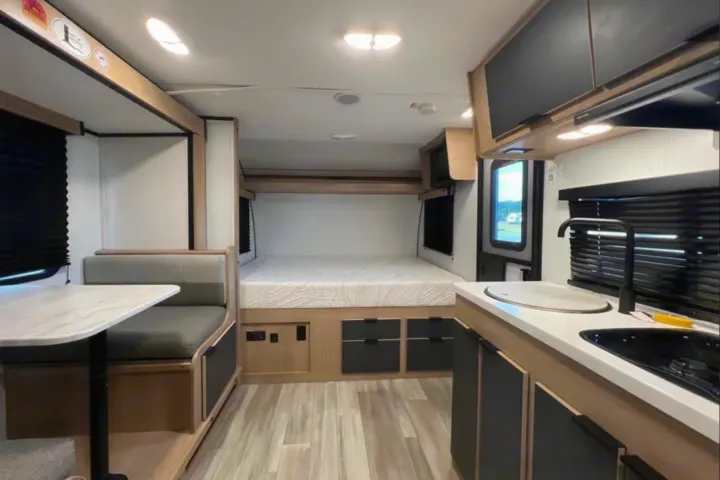 Bright RV rental interior featuring a bed, dinette, and kitchen with modern, light-toned finishes.. Cruiser RV Hitch 2022