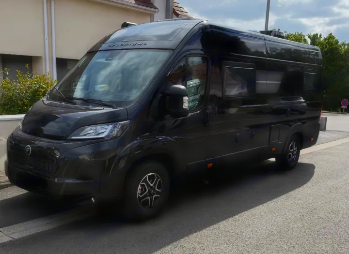 Sleek black Florium "Black Pearl" camper van, perfect for your next rv rental adventure. Parked on a sunny residential street.. FLORIUM BLACK PEARL 63 LJ 2025
