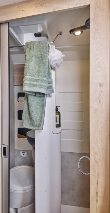 Functional rv rental bathroom featuring a compact toilet, shower, sink, and green towels. Designed for travel comfort.. FLORIUM BLACK PEARL 63 LJ 2025