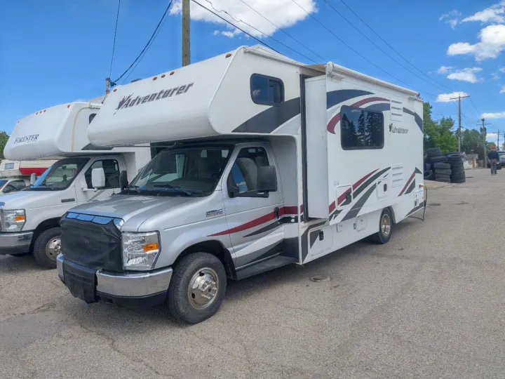Silver Adventurer Class C RV rental parked on asphalt, with another camper behind it under a blue sky.. Adventurer Adventurer Motorhome 2016