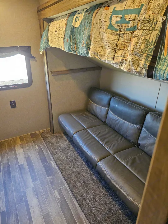 RV rental: interior with cozy bunk bed above a plush gray sofa, mixed flooring, and a window for natural light.. KZ Sportsman 2022