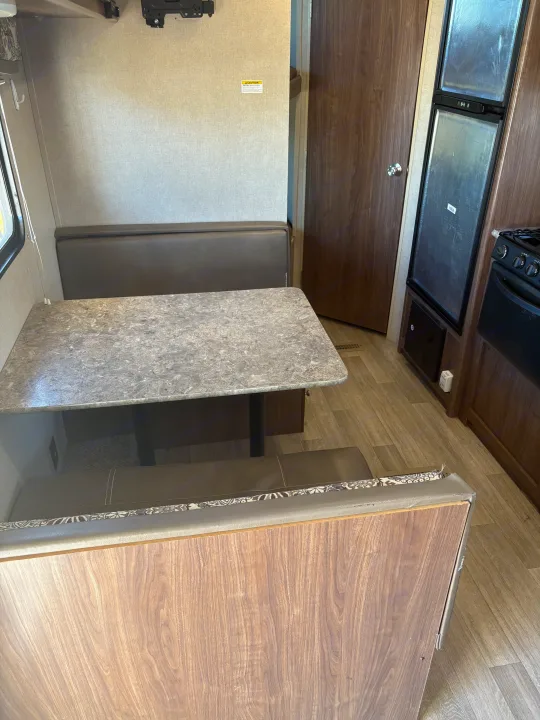 Functional RV rental interior with a dinette, table, bench seating, and an integrated kitchen featuring fridge/stove.. Coleman Lantern 2018