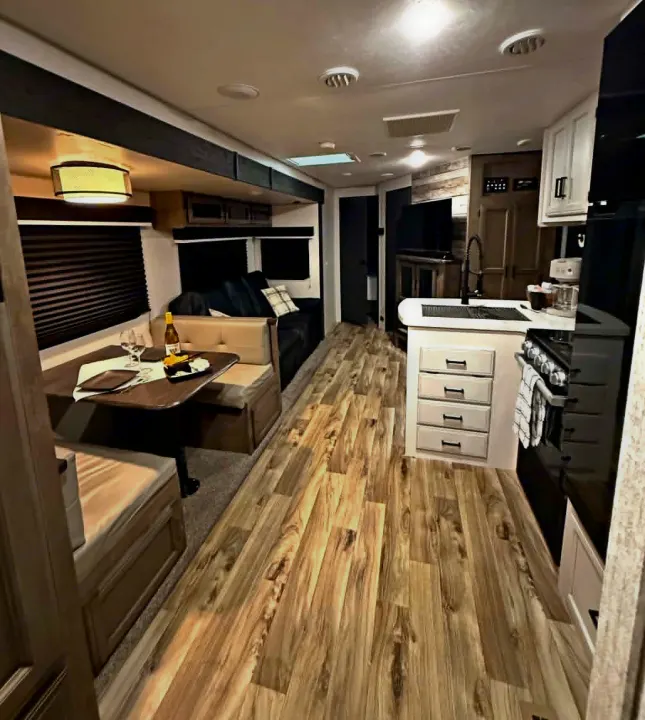 Inviting RV rental interior with a cozy dinette, well-equipped kitchen, and warm wood flooring. Ready for your next adventure.. Venture Other 2022