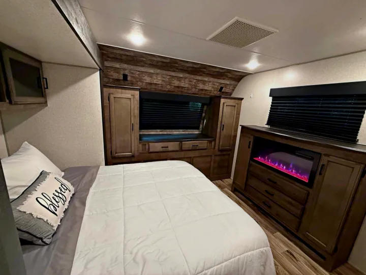 This cozy RV rental bedroom features a comfy bed, warm fireplace, and ample storage, ideal for your next adventure.. Venture Other 2022