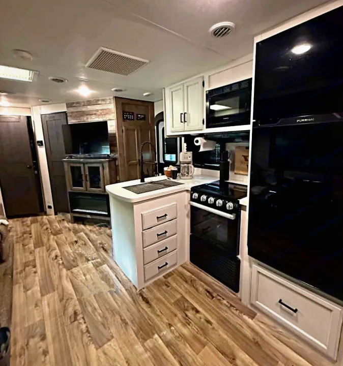 Modern RV rental interior with a full kitchen, wood-look flooring, and a cozy living area, perfect for your next trip.. Venture Other 2022
