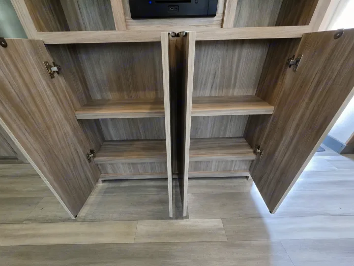 RV rental wood-grain storage cabinets with open doors, revealing two shelves in each compartment for belongings.. Minnie Minnie Trailer 2022