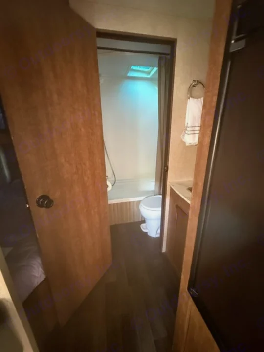 Functional RV rental bathroom featuring a shower, toilet, and vanity, with a glimpse of the bedroom.. Starcraft Autumn Ridge Outfitter 2018