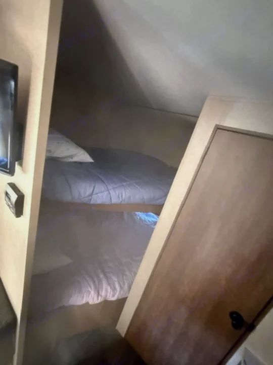 Cozy bunk beds inside an RV rental. This compact sleeping area includes a TV to the left and a closed door on the right.. Starcraft Autumn Ridge Outfitter 2018