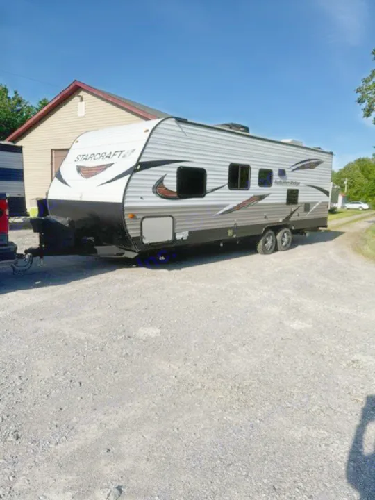 Explore the outdoors! Starcraft Autumn Ridge travel trailer, perfect for your next rv rental. Parked on gravel on a sunny day.. Starcraft Autumn Ridge Outfitter 2018