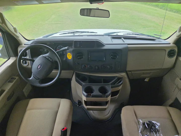Front cabin of an E-Series rv rental, showing dashboard, steering wheel, and front seats. A 'CAUTION HEIGHT' sticker is on the dash.. Winnebago Minnie Winnie 2019