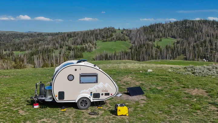 An rv rental teardrop camper (Boondock model) is set up for off-grid adventure with solar panels & generator in a scenic landscape.. nuCamp T@B 2022