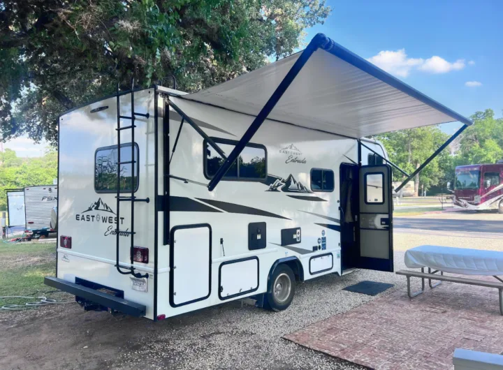 White East West Entrada rv rental parked at a campsite, awning extended for shade. Ready for travel & camping adventures.. East to West Entrada 2026