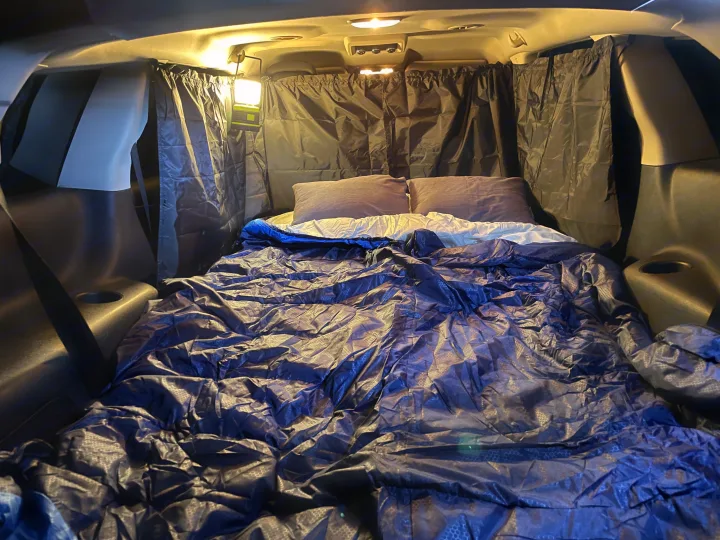 Cozy car camping setup in a vehicle with blackout curtains and bed, creating an RV rental alternative for comfortable sleep.. Dodge Journey 2016