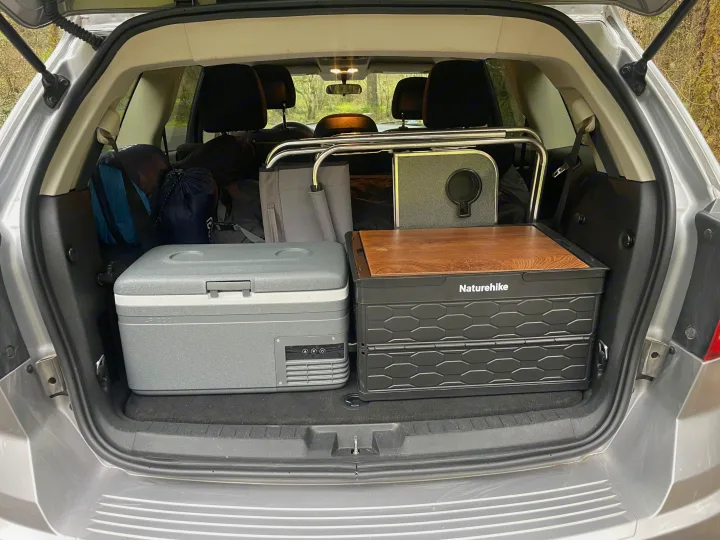 Back of a car packed with camping gear: a cooler, storage crate, and bags, perfect for an RV rental adventure.. Dodge Journey 2016
