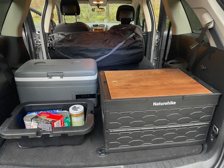 Organized RV rental trunk: A grey Alpicool portable fridge, a black Naturehike storage box, and a food bin for car camping.. Dodge Journey 2016