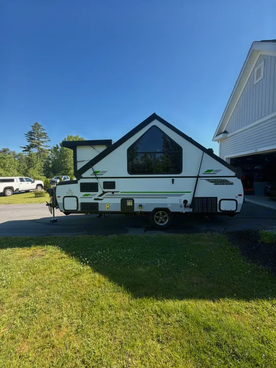 Ready for adventure! This unique A-frame camper, a perfect RV rental, sits on a driveway under a clear sky.. Forest River Rockwood Premier 2021