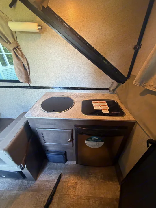 Compact rv rental kitchen features a sink, 2-burner stove, and fridge, providing all galley essentials for travelers.. Forest River Rockwood Premier 2021