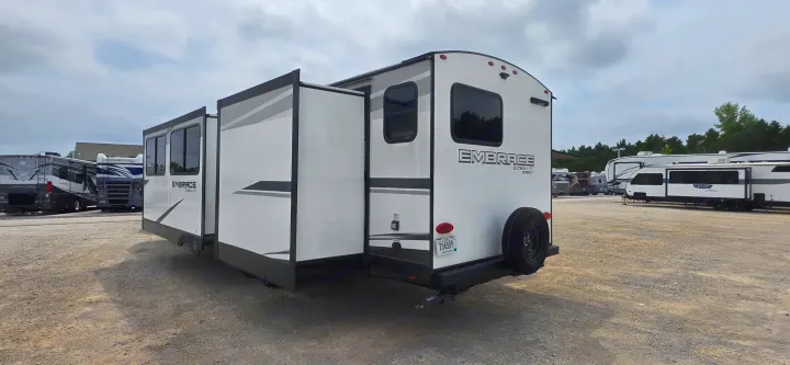 Rear-side view of a white Embrace Ultra-Lite travel trailer with extended slide-outs, perfect for an rv rental.. Cruiser RV 2024