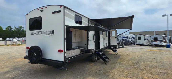 White Embrace Ultra-Lite travel trailer RV showcasing an outdoor kitchen, deployed awnings, and entry steps; great for RV rental.. Cruiser RV 2024