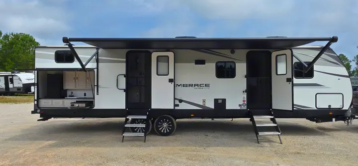 Embrace Ultra-Lite travel trailer RV rental with an extended awning, open doors, and an outdoor kitchen area.. Cruiser RV 2024