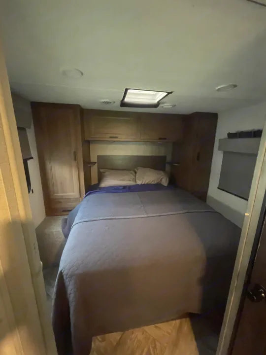 Cozy RV rental bedroom with a comfortable bed, overhead cabinets, and a skylight for natural light.. Forester LE 2022