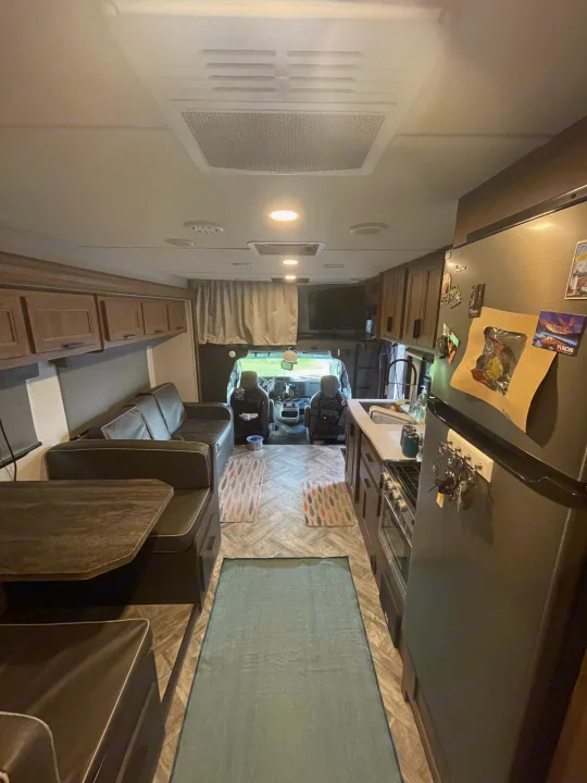 This RV rental interior shows a cozy living area with a couch and dinette, a full kitchen, and the front driver's cabin.. Forester LE 2022