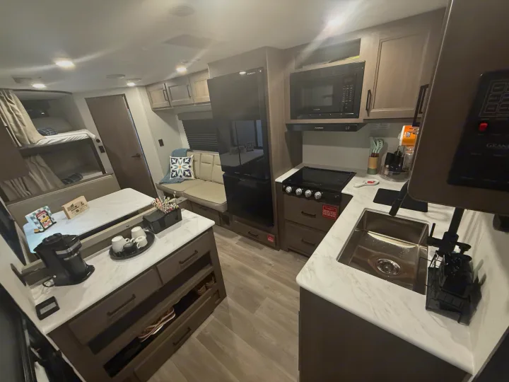 Bright rv rental interior: full kitchen with stove, microwave, sink, plus dinette & bunk beds for cozy family trips.. Grand Design Transcend Xplor 2026
