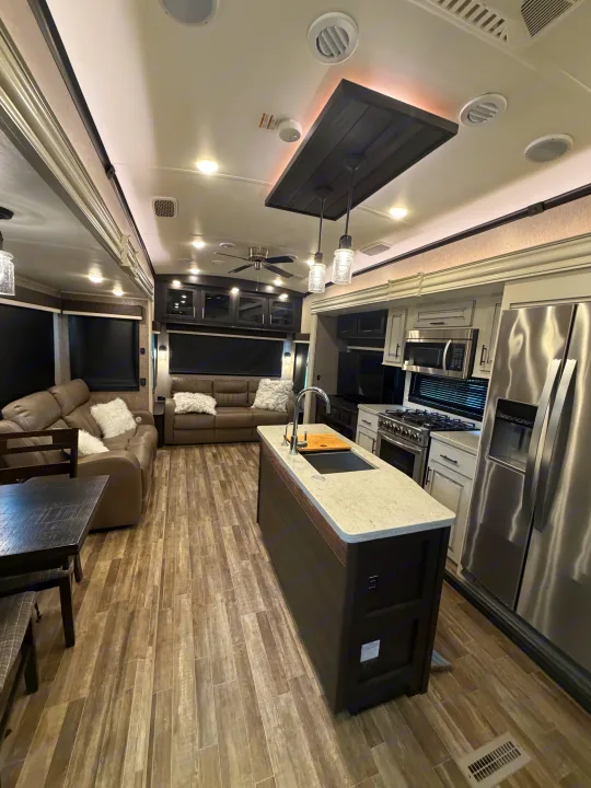 This inviting RV rental interior features a modern kitchen, living room with sofas, and wood-look flooring.. Jayco North Point 2021