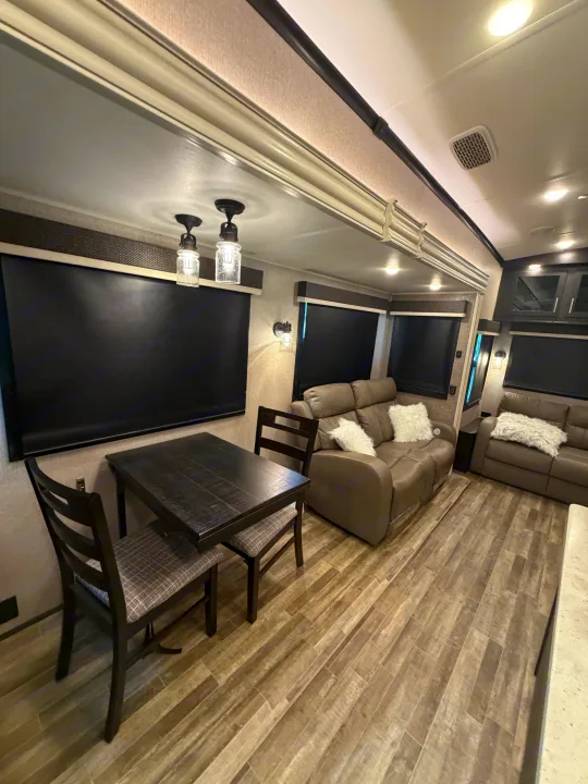 Comfortable RV rental living & dining area with recliners, table, and stylish wood-look flooring.. Jayco North Point 2021