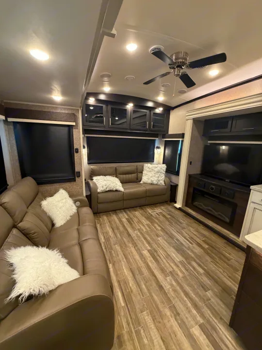This modern RV rental living space features cozy recliners with fluffy pillows, a fireplace, TV, stylish cabinetry, and wood-look flooring.. Jayco North Point 2021