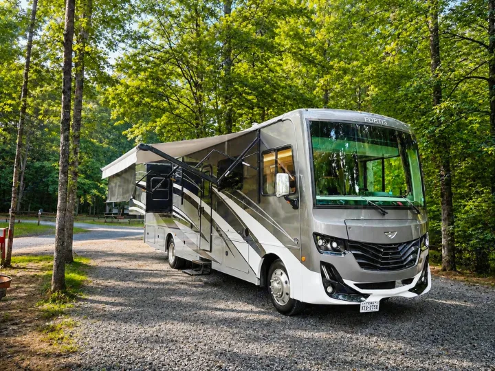 This Fortis RV rental is perfectly set up at a shaded, green campsite with awnings extended, ready for adventure.. Fleetwood Fortis 2021