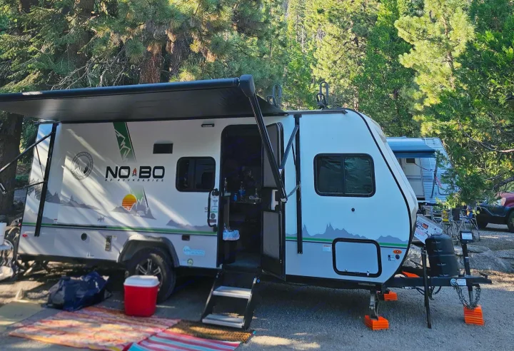RV rental: NO BOUNDARIES travel trailer at a shaded forest campsite. Awning extended, outdoor rugs out. Ready for adventure.. No Boundaries 19 2022