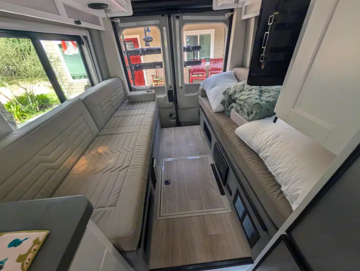 Cozy rv rental interior featuring two long bench beds, a central walkway, and rear windows, perfect for travel.. Coachmen Beyond 2023
