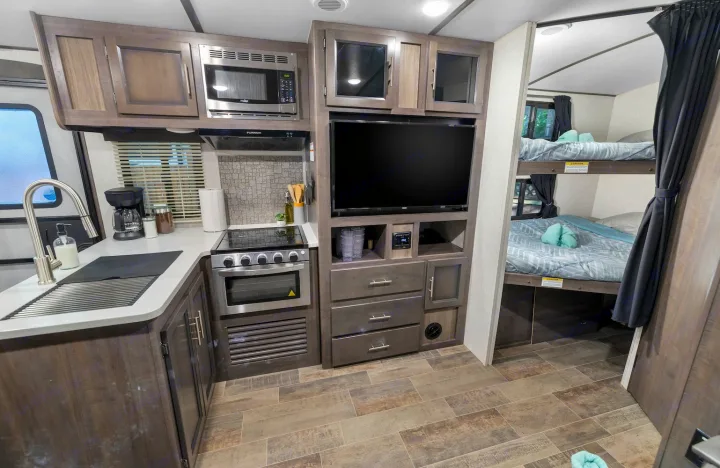 This rv rental features a modern interior: a functional kitchen, entertainment TV, and cozy bunk beds for family trips.. Crossroads RV Sunset Trail Super Lite 2022