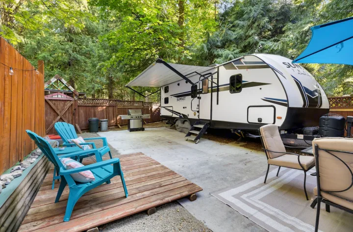 This inviting rv rental setup features an RV with an extended awning, a grill, and a patio with chairs nestled in nature.. Crossroads RV Sunset Trail Super Lite 2022