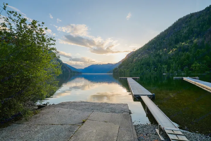 Scenic lake with docks & mountains at sunset, perfect for an RV rental adventure. Calm waters reflect the sky.. Crossroads RV Sunset Trail Super Lite 2022