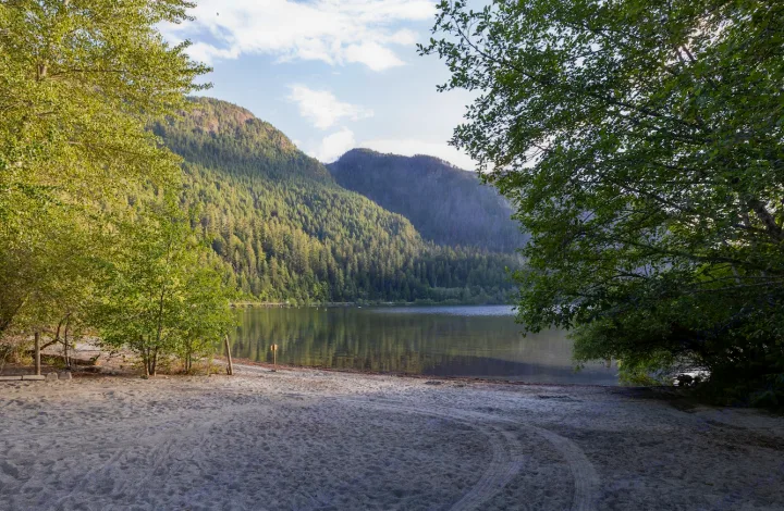 This serene beach by a forested lake and mountains is an ideal RV rental destination.. Crossroads RV Sunset Trail Super Lite 2022