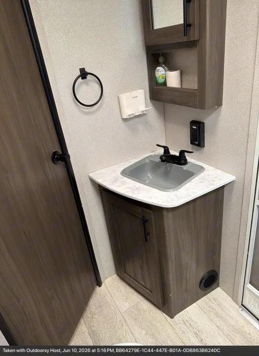 RV rental bathroom with a gray sink, dark wood cabinet, soap, and towel ring. Clean and functional space.. Forest River Shasta 2021