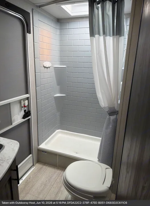 Clean and compact RV rental bathroom featuring a shower, toilet, and gray subway tile-look walls. Ideal for camping and travel.. Forest River Shasta 2021