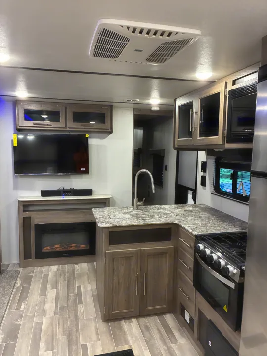 Modern rv rental interior with a fully equipped kitchen, TV, and electric fireplace, perfect for comfortable travel.. Crossroads RV Zinger 2021