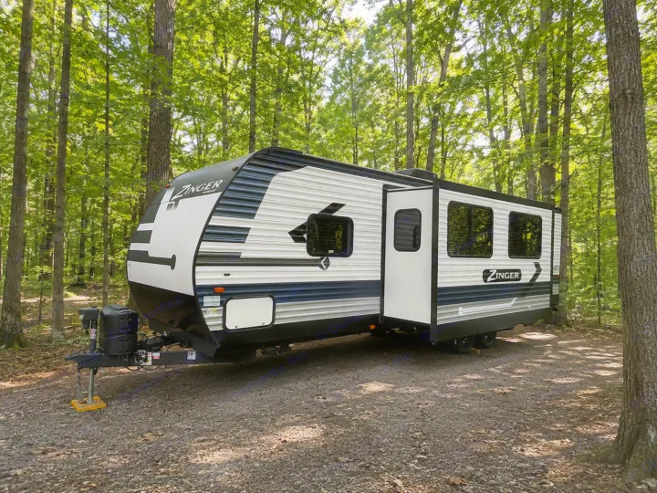 This Zinger travel trailer RV rental is parked in a lush forest campsite. Your perfect camping adventure awaits!. Crossroads RV Zinger 2021