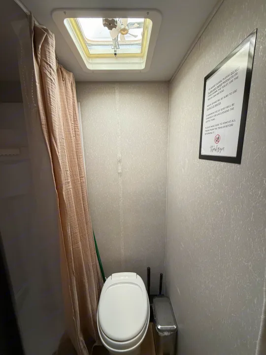 RV rental compact bathroom with toilet, shower curtain, skylight, and essential rules for septic tank use.. Forest River Cherokee Wolf Pup 2021
