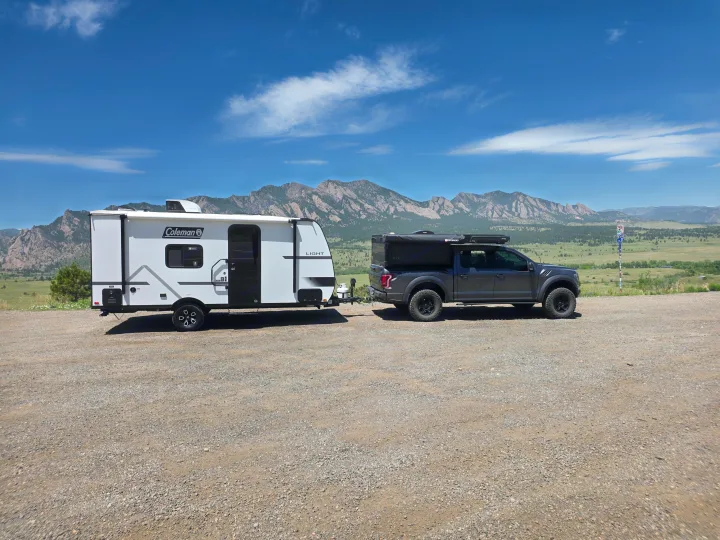 Explore with this RV rental: A truck with an overland camper tows a Coleman travel trailer against a mountain backdrop.. coleman 17rx 2026