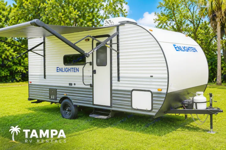 White & grey Enlighten travel trailer RV rental on grass, ready for your outdoor adventures. Awning extended.. Gulf Stream Enlighten Super Lite 2025