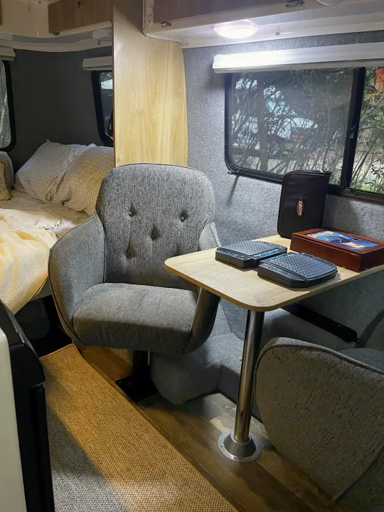 Cozy RV rental interior featuring a comfy bed, gray chairs, a table with games, ideal for travel and relaxation.. Casita Freedom 2024