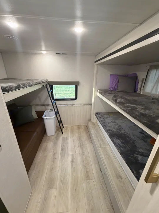 RV rental bunkroom: Light-filled interior with multiple bunk beds, cozy seating, wood-look floor, and a window.. Forest River Surveyor Legend 2024